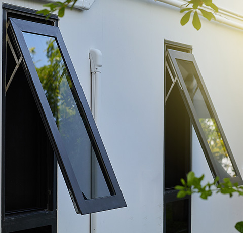 two opened black windows on a white wall surrounded by greenery showcasing natural light and ventilation options for a modern home 3 design features