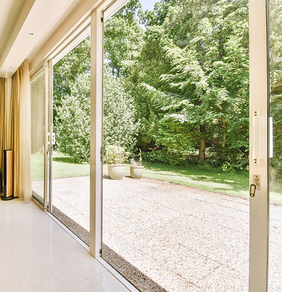 interior view with sliding glass doors showcasing a lush green garden and outdoor planters five vibrant plants surrounded by trees
