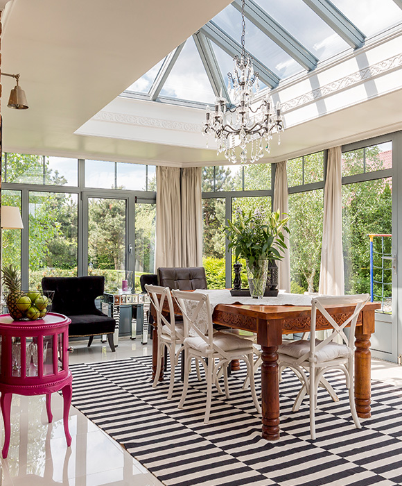 bright and airy dining room with a large table and floral centerpiece featuring a chandelier and large windows showcasing outdoor greenery suitable for 13 guests
