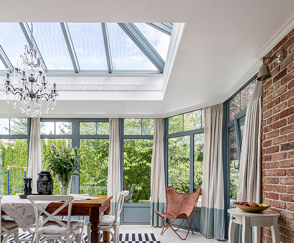 modern sunroom with a glass ceiling elegant chandelier and brick wall featuring a wooden dining table and stylish decor suitable for 13 inviting gatherings